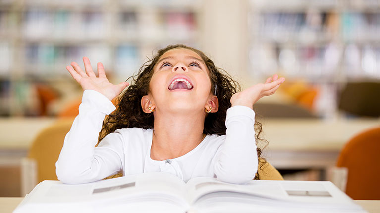 Photo of a girl with a book, with her hands in the air