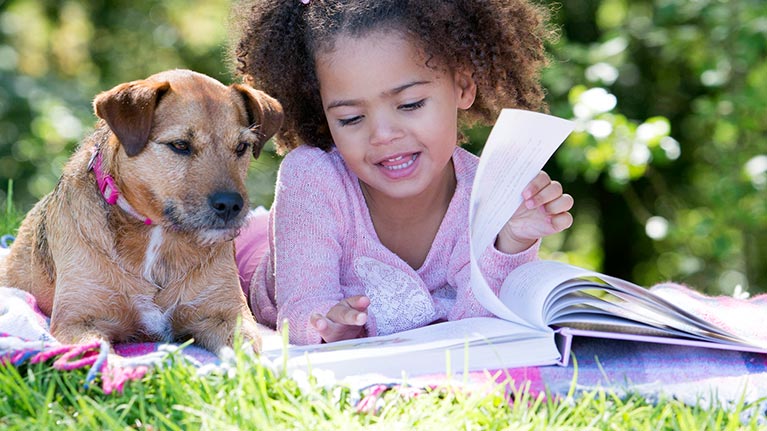 Photo of a girl reading with a dog