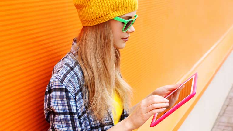 Photo of a girl in sunglassess reading on a tablet